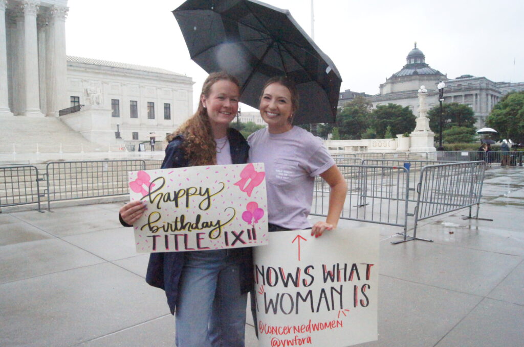 Two women holding Title IX signs in front of SCOTUS.