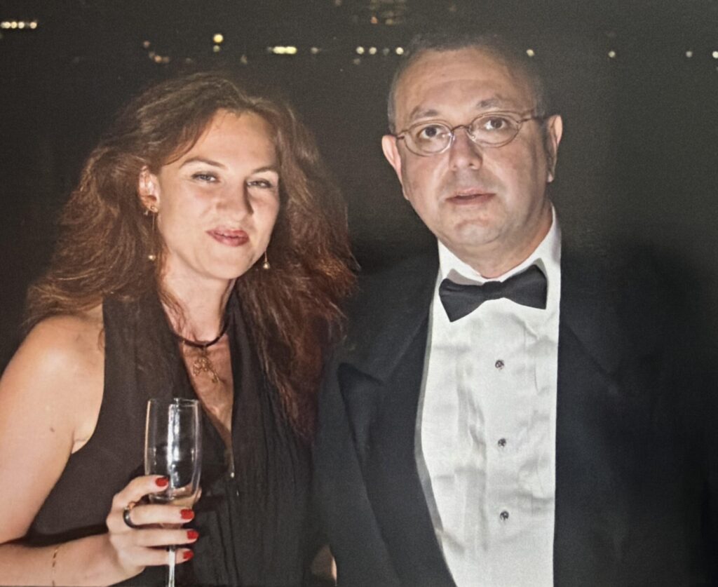 Man in tuxedo and woman in black dress at night.